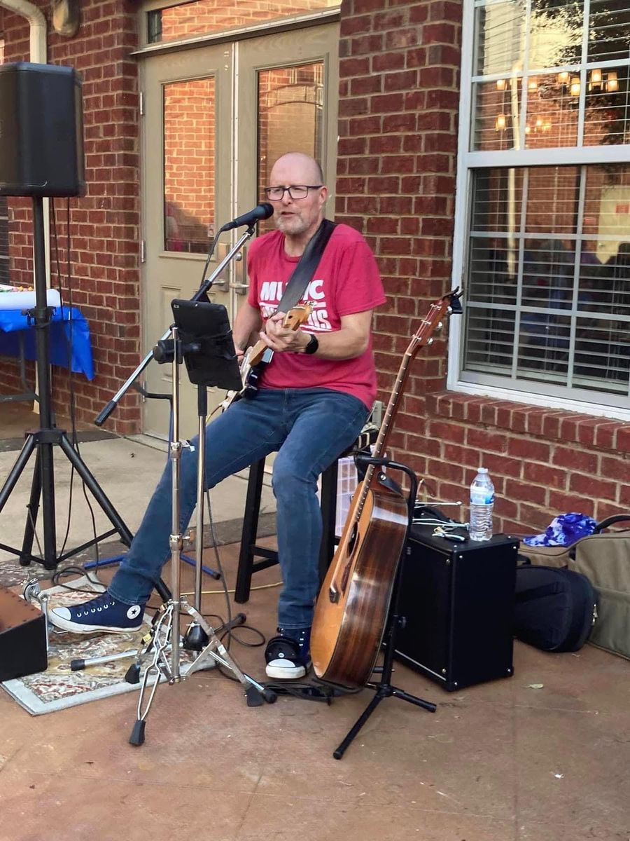Chris performing with an acoustic guitar at an outdoor concert