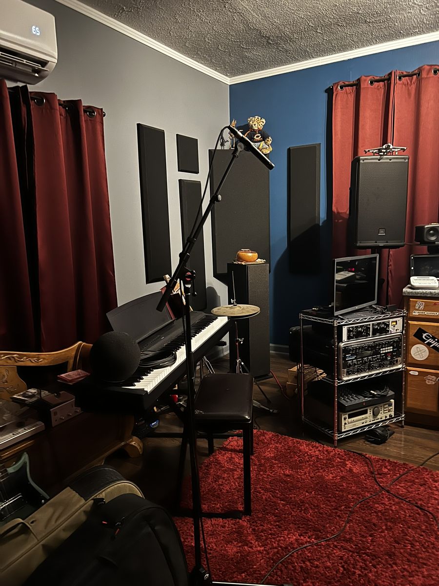 Studio corner with a keyboard, microphone stand and acoustic panels